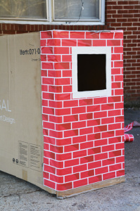 Cardboard box playhouse - trim first window with white tape